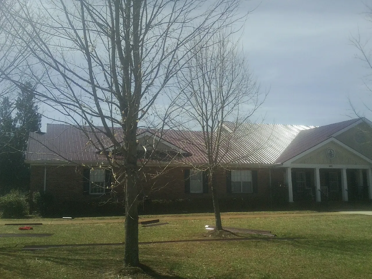 Red metal roof on a brick building seen from the front lawn in Saint Johnsville