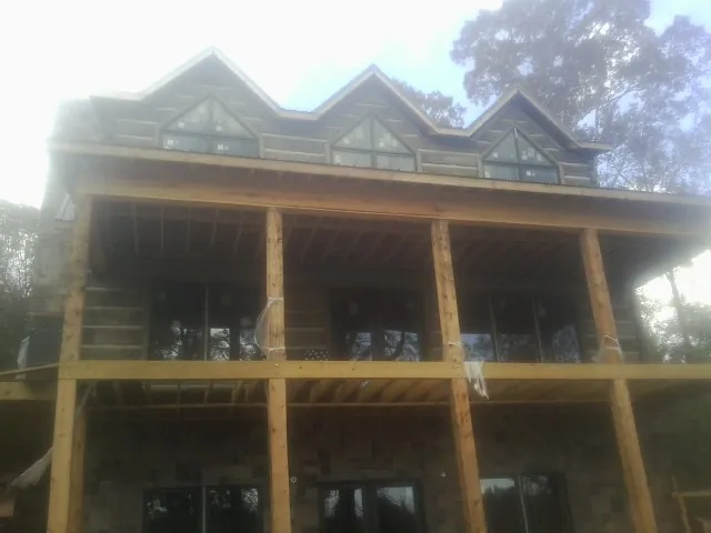Dormers and porch framing on a large log home under construction — Roof Coating work by our crew in Saint Johnsville