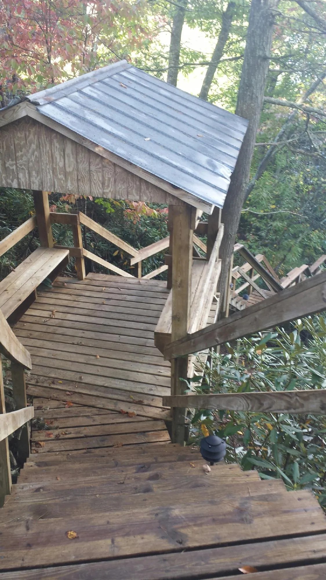 Metal roofed shelter over wooden steps on a wooded walkway — Skylight Repair & Installation work by our crew in Saint Johnsville