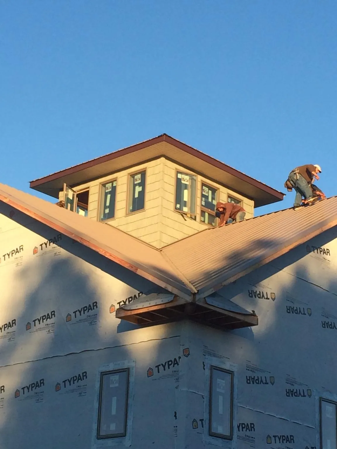 Roofers working around a rooftop cupola on a new metal roof at sunset — Roof Waterproofing in Saint Johnsville by Roofing Brothers